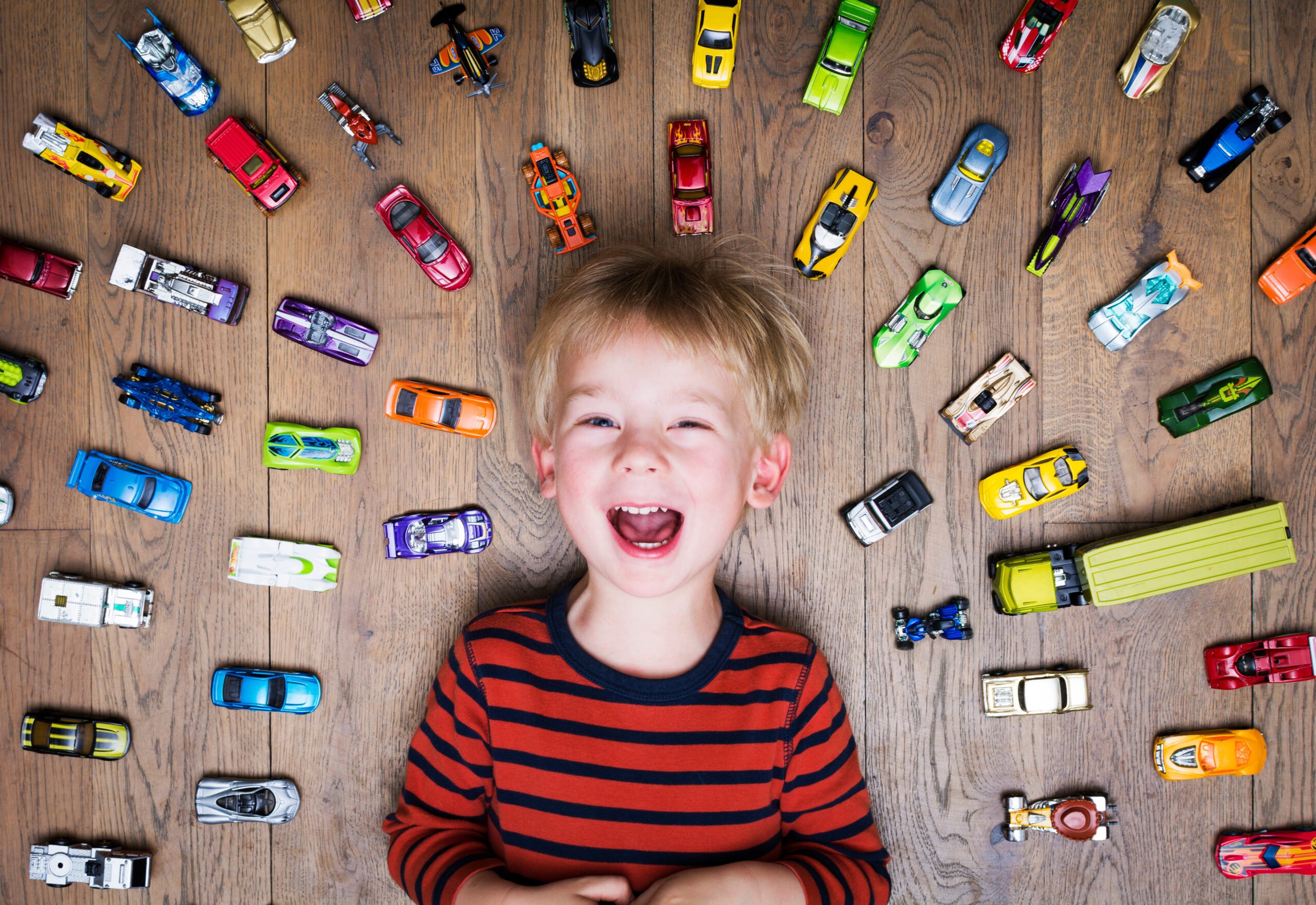 Boy with toy cars on floor laughing