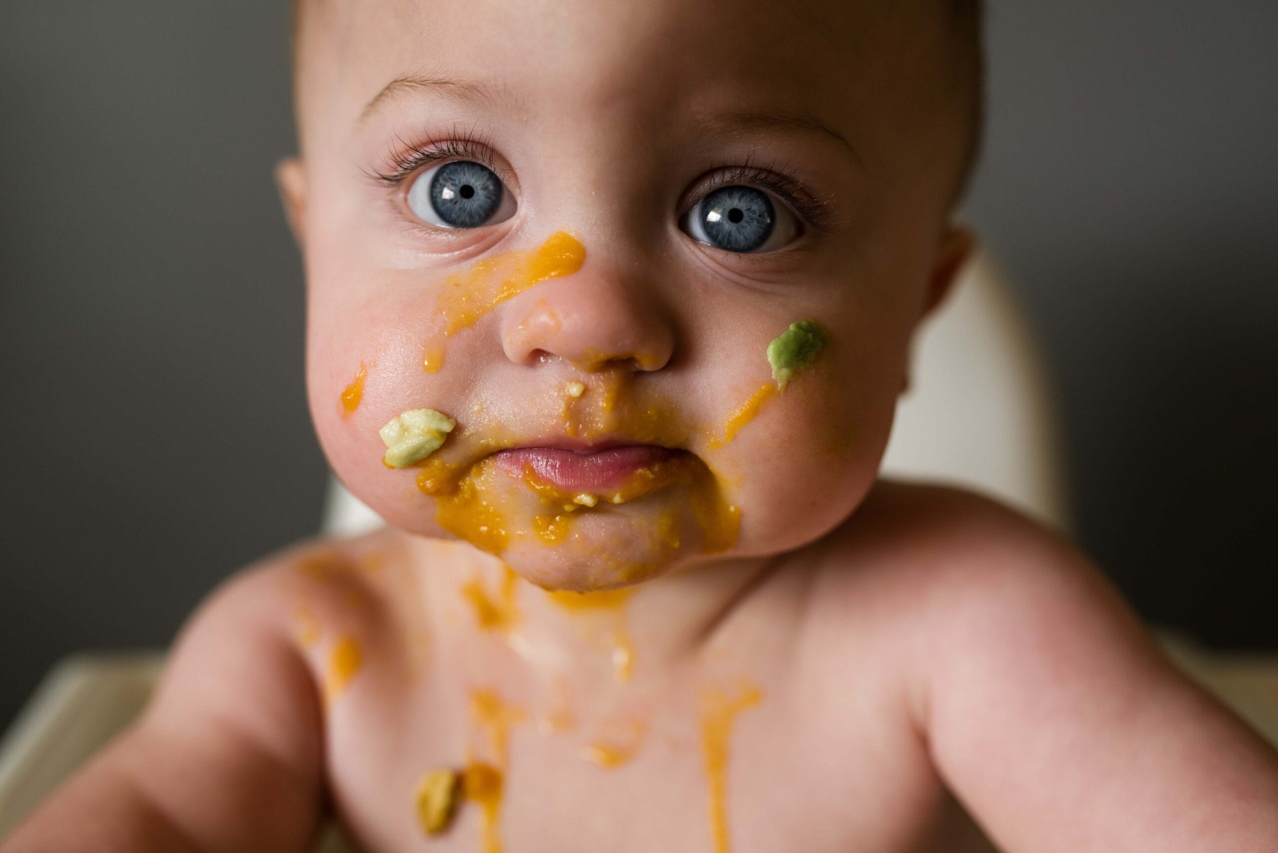 Infant starting solids with food on face